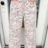 Person wearing floral pants standing in front of a door.
