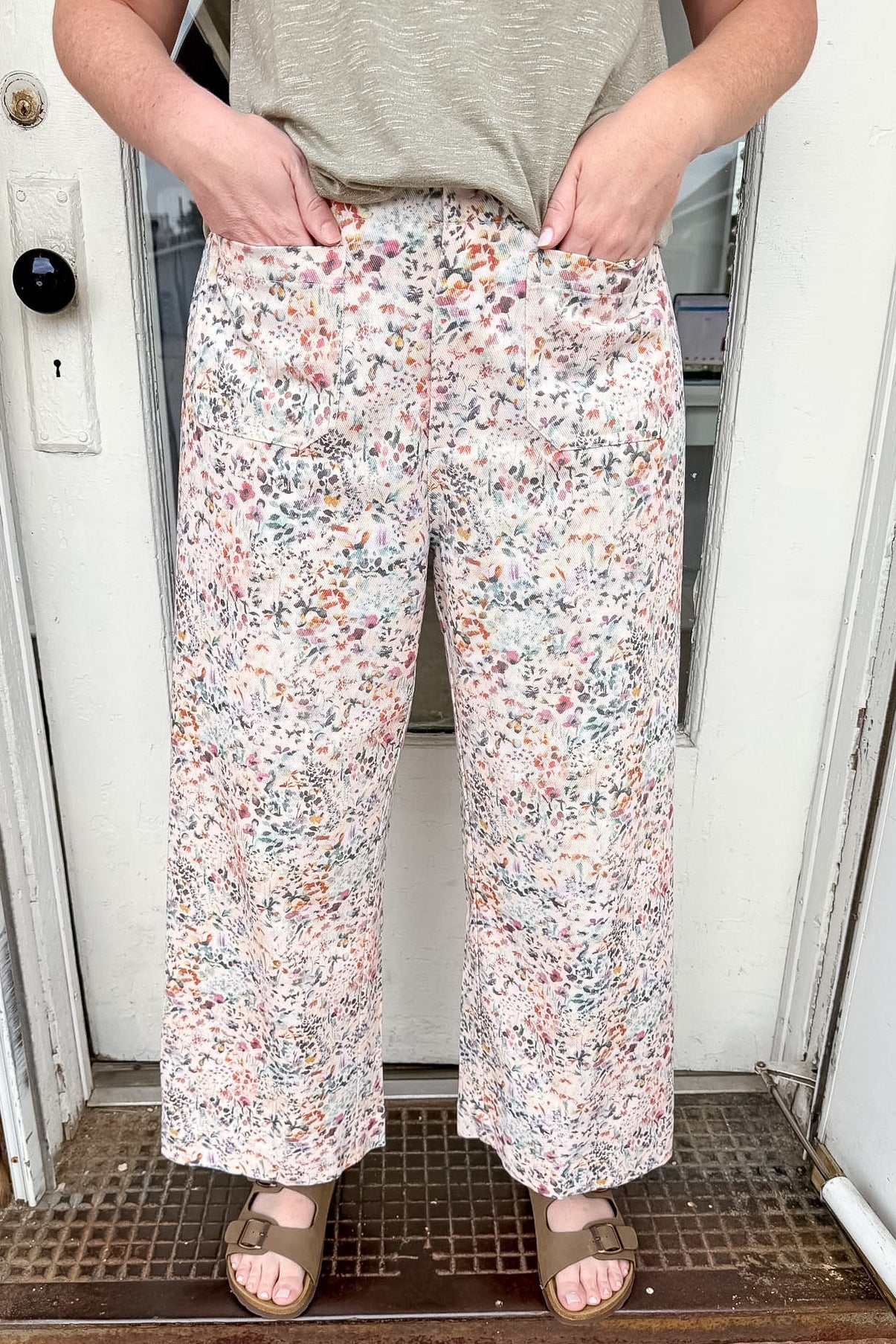 Person wearing floral pants standing in front of a door.