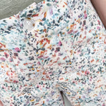 Floral patterned pants with a button detail on a neutral background