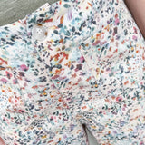 Floral patterned pants with a button detail on a neutral background