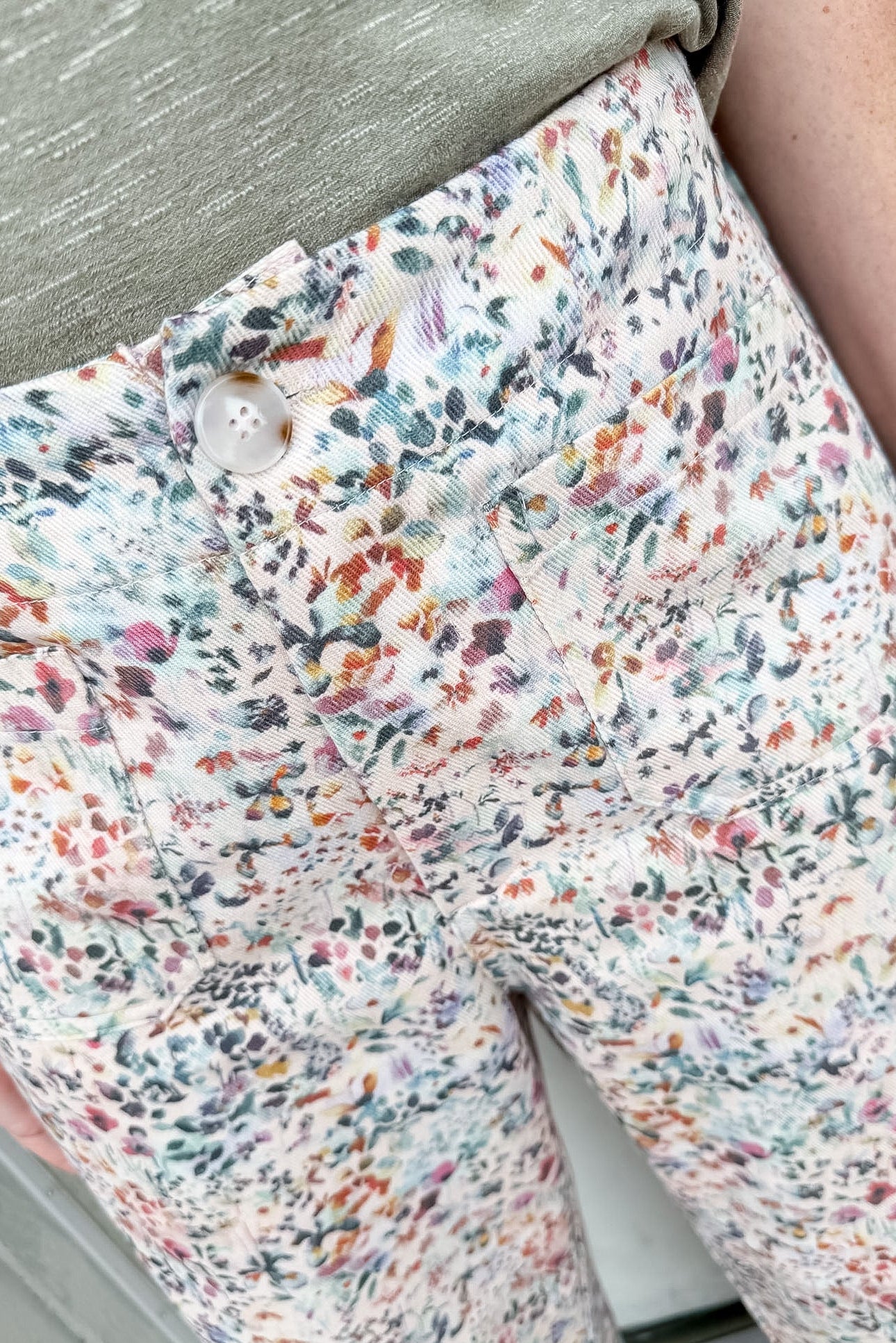 Floral patterned pants with a button detail on a neutral background