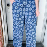 Person wearing blue floral pants standing in a doorway.
