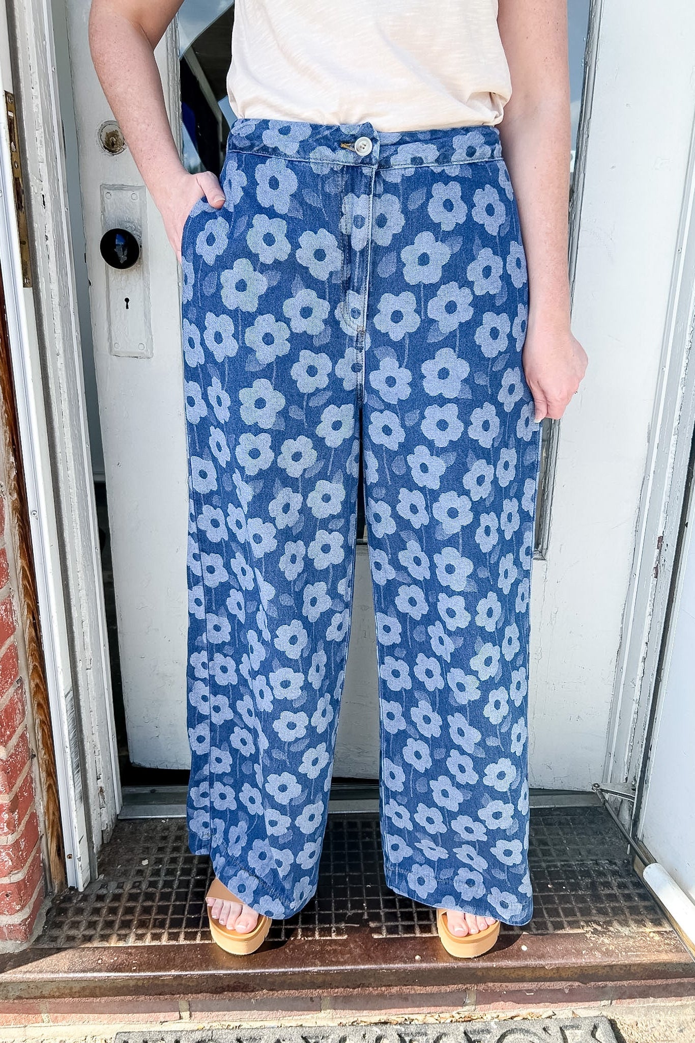 Person wearing blue floral pants standing in a doorway.