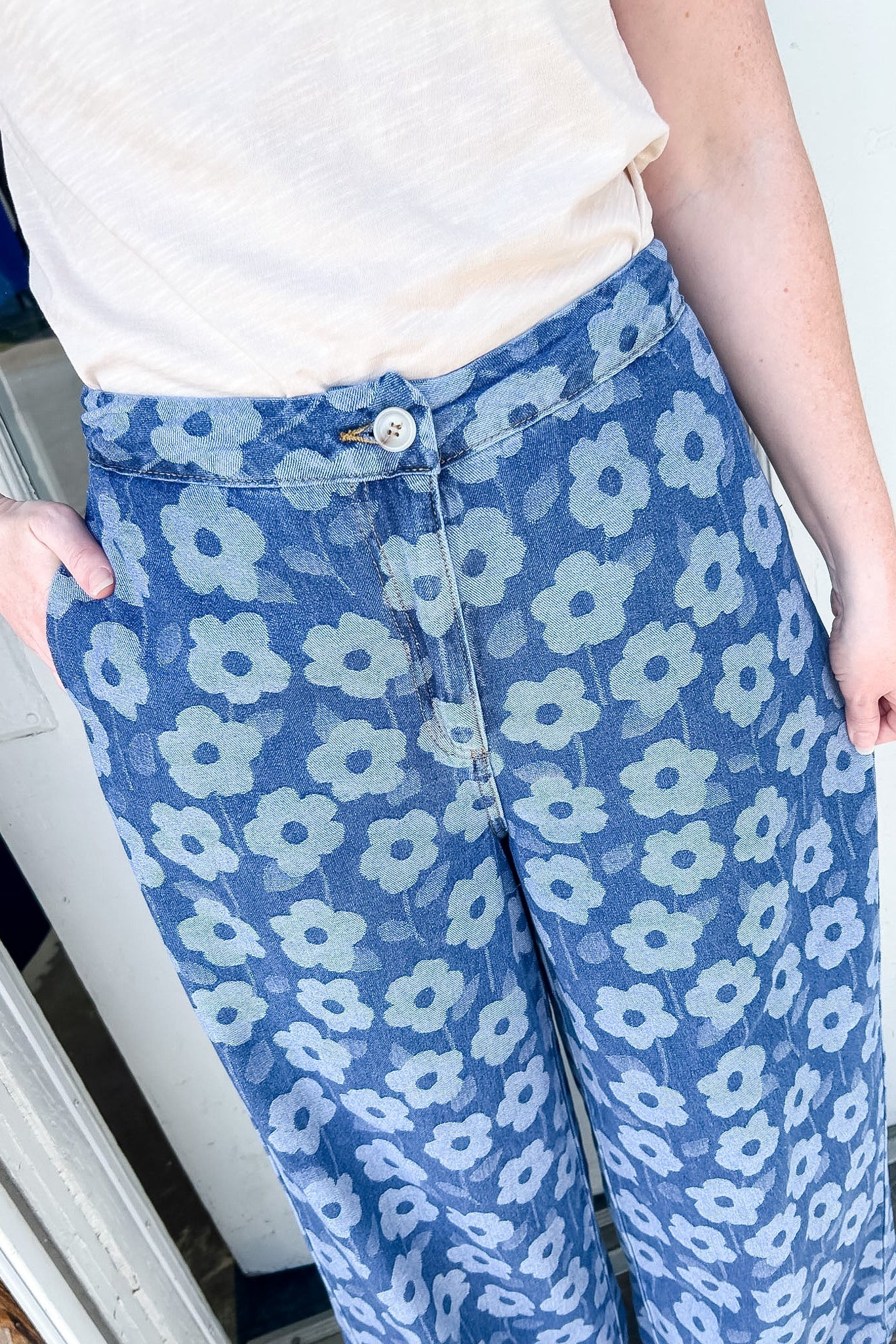 Floral print pants with a white tanks. The model has her hand on her hip.