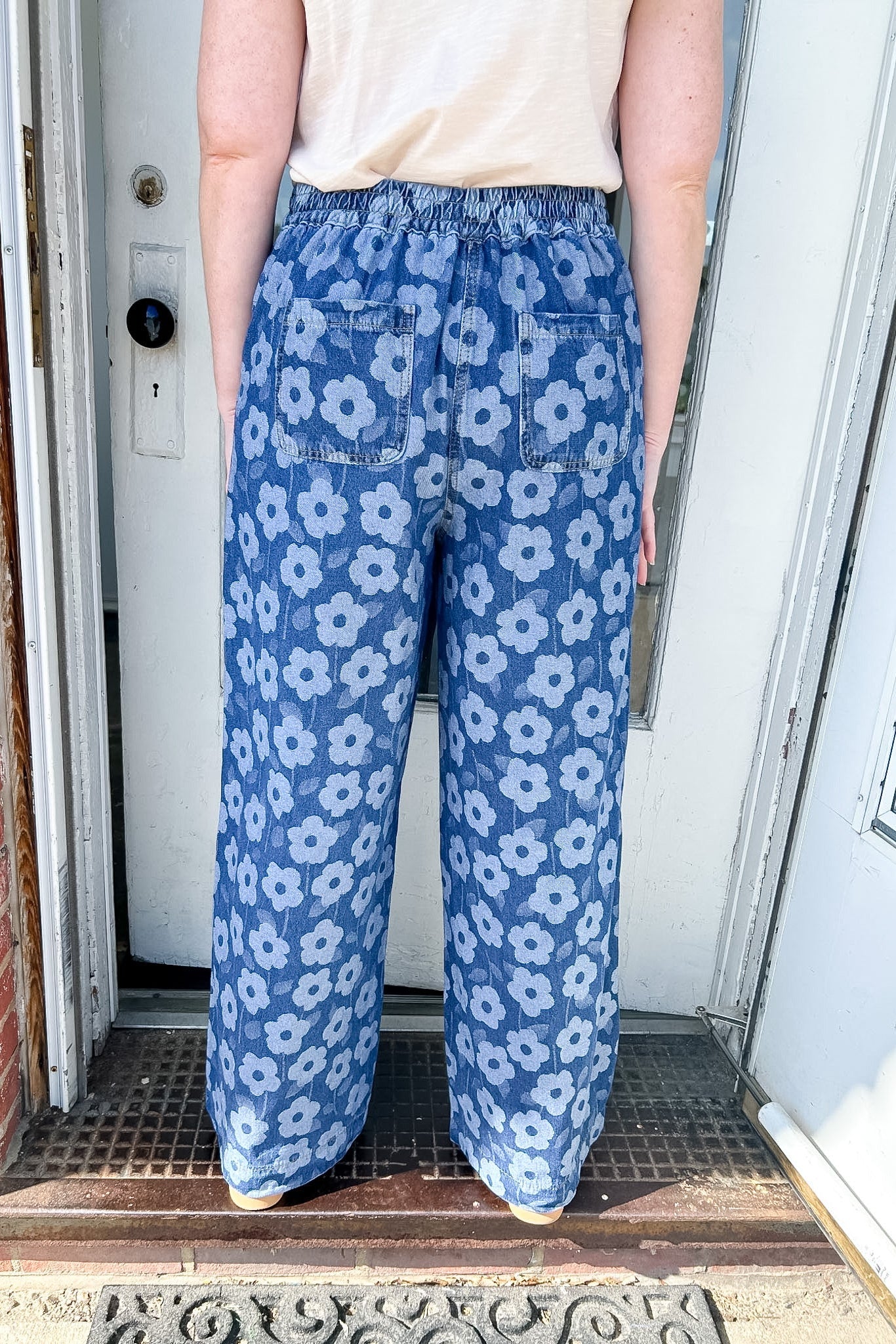 Person wearing blue floral pants standing in front of a door.