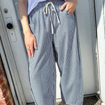 Person wearing a white t-shirt and blue checkered pants standing in front of a door.