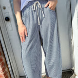 Person wearing a white t-shirt and blue checkered pants standing in front of a door.