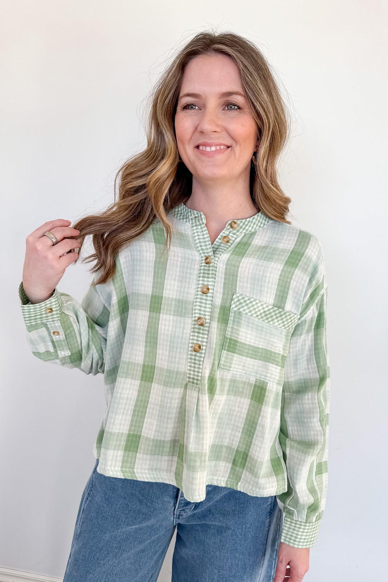 Woman wearing a green plaid shirt and blue jeans against a white background