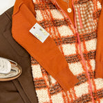 Plaid vest over a brown sweater with a white background