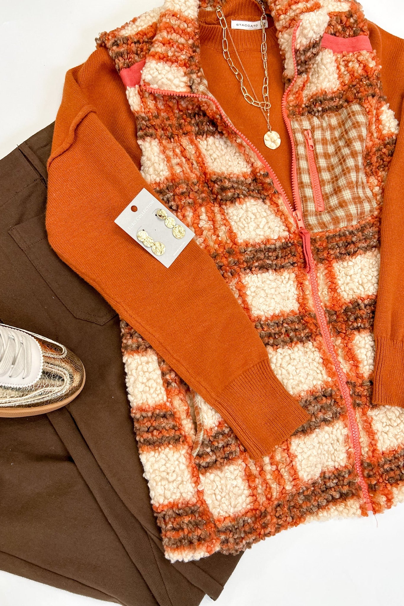 Plaid vest over a brown sweater with a white background