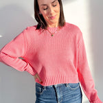 Woman wearing a pink sweater and blue jeans against a white background