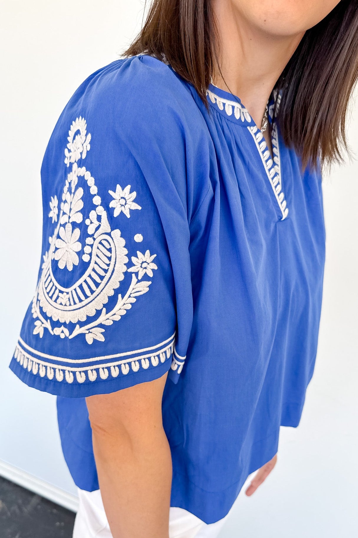 Blue top with white embroidery on a plain background