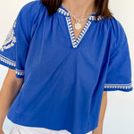 Woman wearing a blue top with white trim against a white background