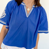 Woman wearing a blue top with white trim against a white background