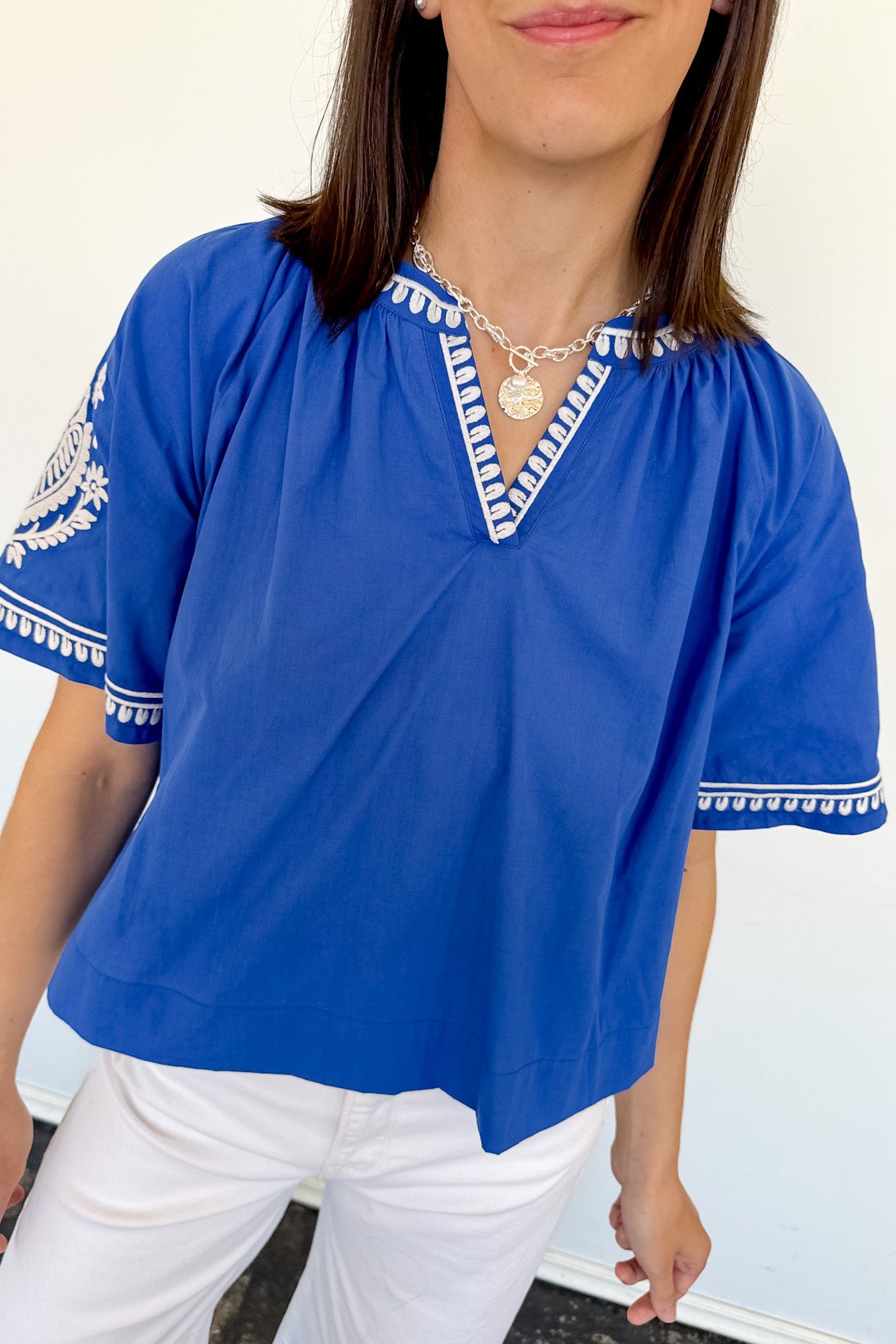 Woman wearing a blue top with white trim against a white background