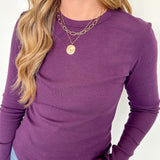 Person wearing a purple long-sleeve top with a white background