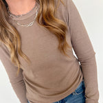 Person wearing a brown long-sleeve top and blue jeans on a white background
