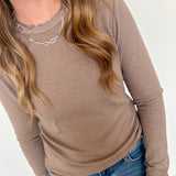 Person wearing a brown long-sleeve top and blue jeans on a white background