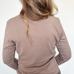 Person wearing a brown long-sleeve top and blue jeans on a white background