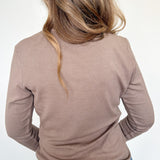 Person wearing a brown long-sleeve top and blue jeans on a white background