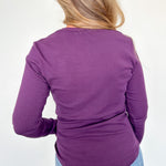 Person wearing a purple long-sleeve top and blue jeans on a white background