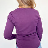 Person wearing a purple long-sleeve top and blue jeans on a white background