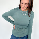 Woman wearing a green sweater and blue jeans against a white background