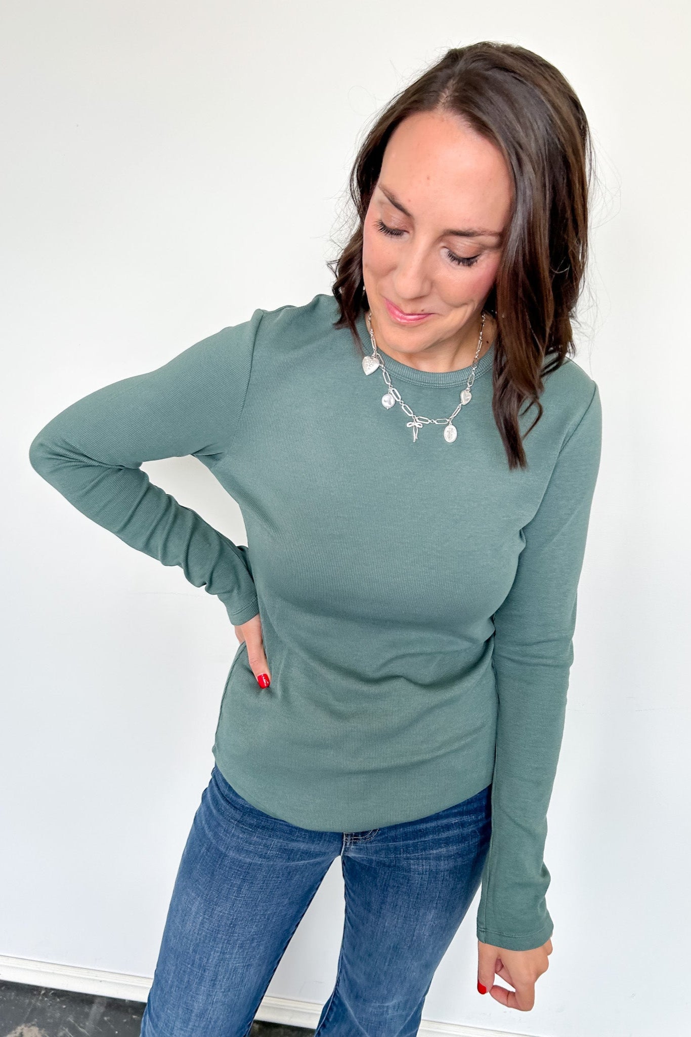 Woman wearing a green sweater and blue jeans against a white background