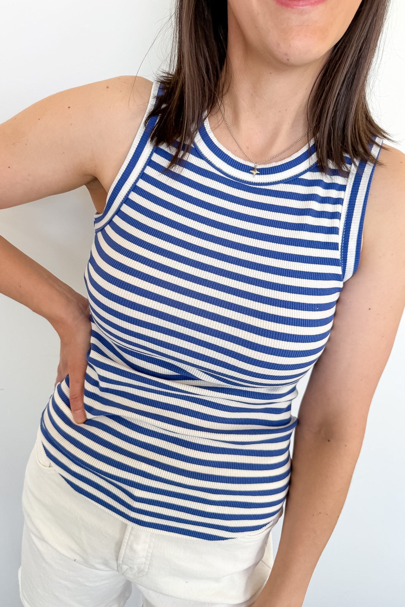 Person wearing a blue and white striped tank top against a plain background