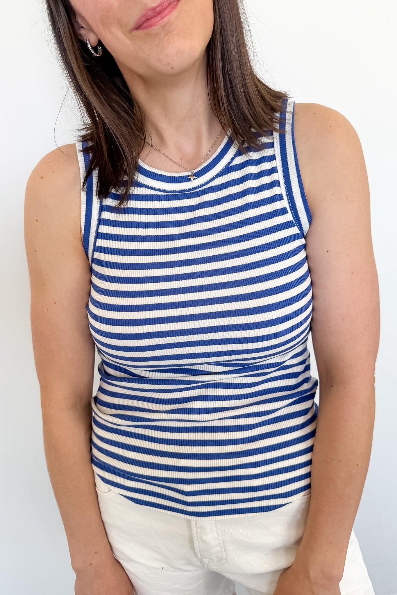 Woman wearing a blue and white striped tank top against a plain background