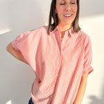 Woman wearing a red and white striped shirt against a white wall