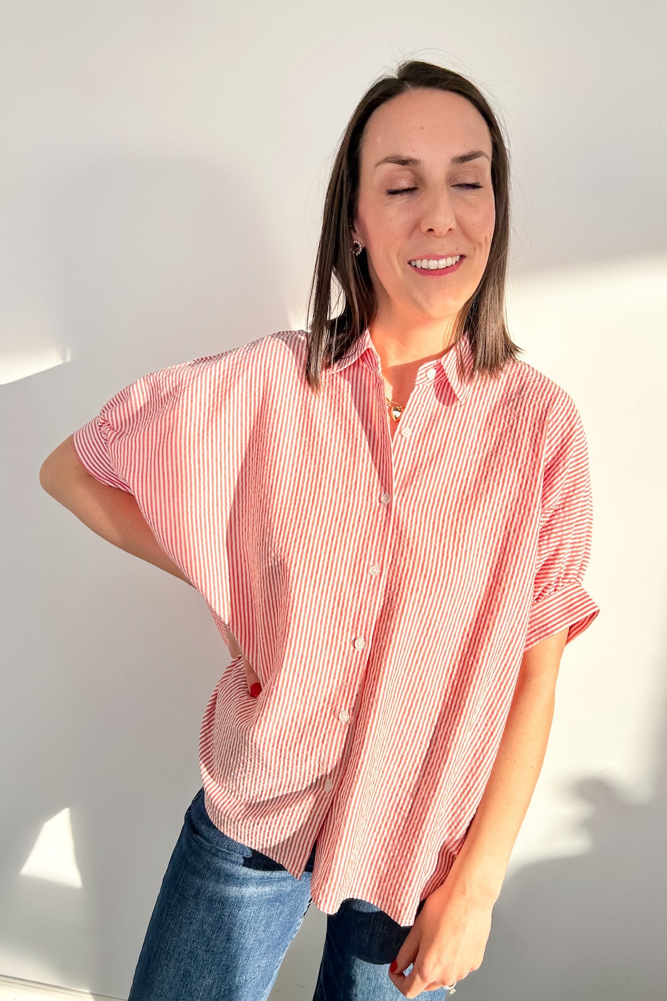 Woman wearing a red and white striped shirt against a white wall