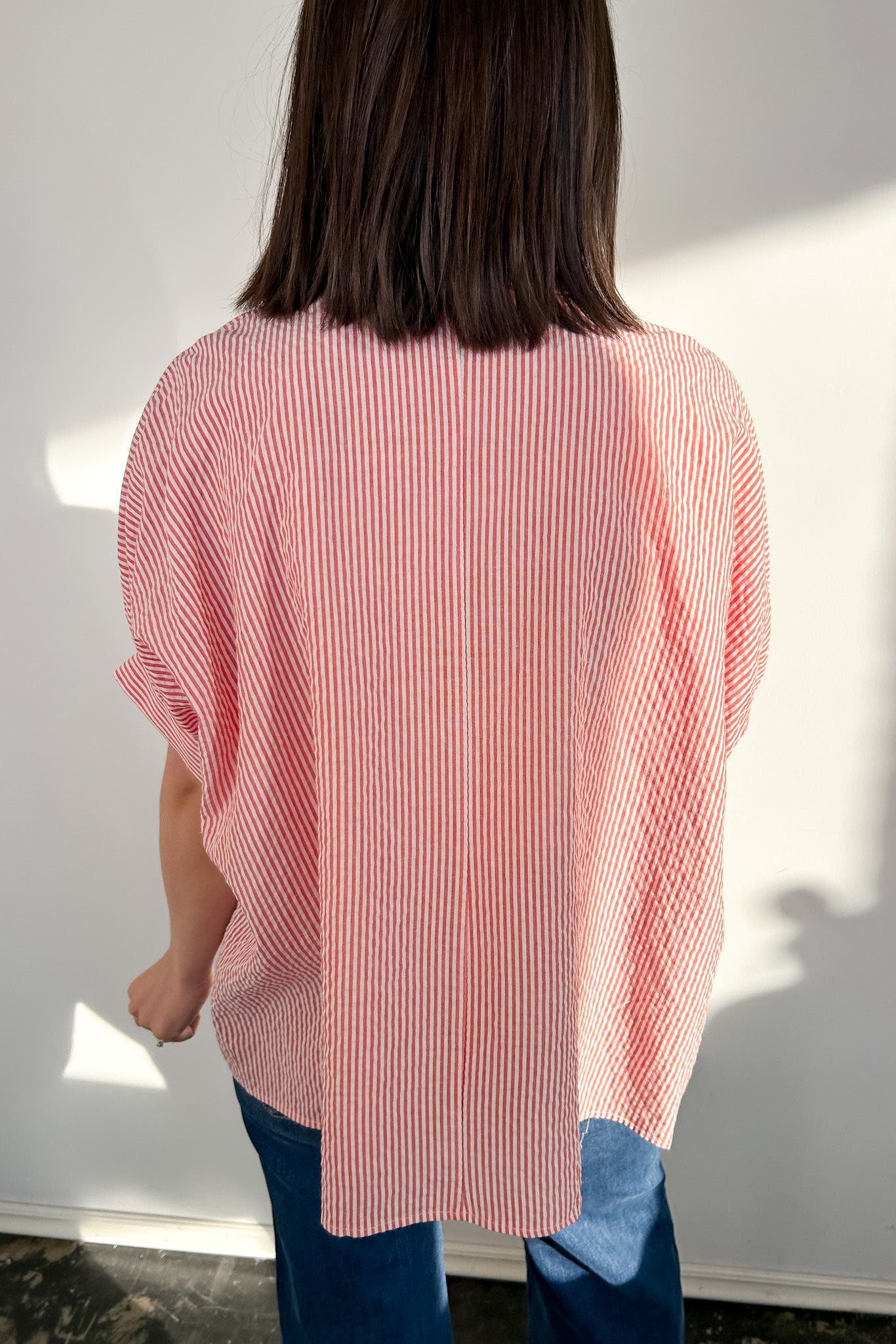 Person wearing a red and white striped shirt with a plain background