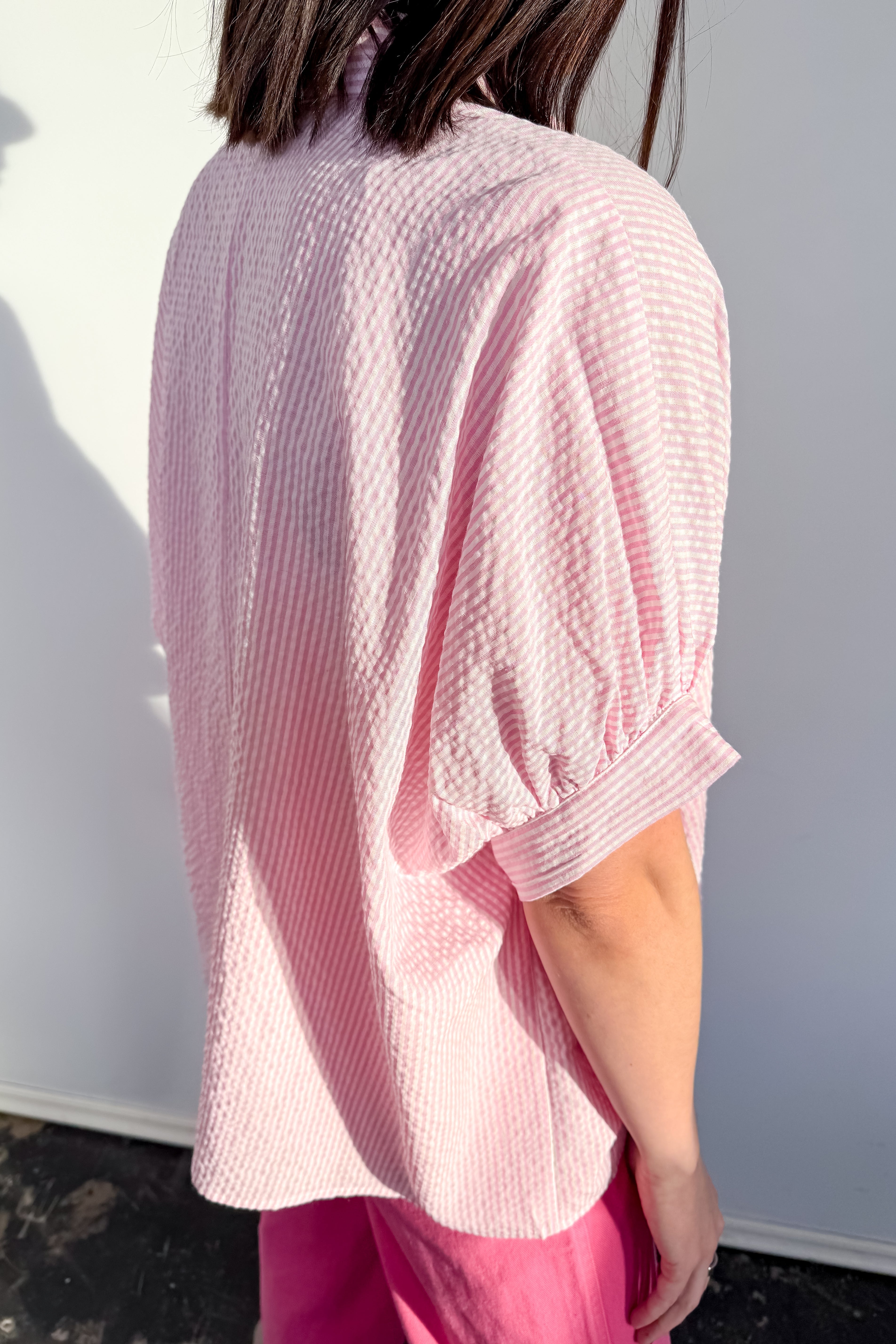 Person wearing a pink textured blouse against a white background