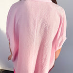 Person wearing a pink textured shirt against a white wall