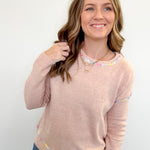 Woman wearing a beige sweater with colorful accents on a white background