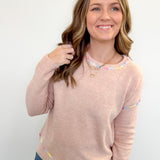 Woman wearing a beige sweater with colorful accents on a white background