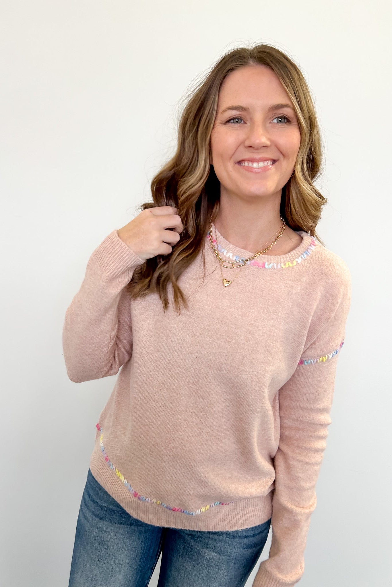 Woman wearing a beige sweater with colorful accents on a white background