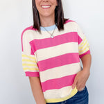 Woman wearing a pink and yellow striped sweater against a white background