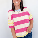 Woman wearing a pink and yellow striped sweater against a white background