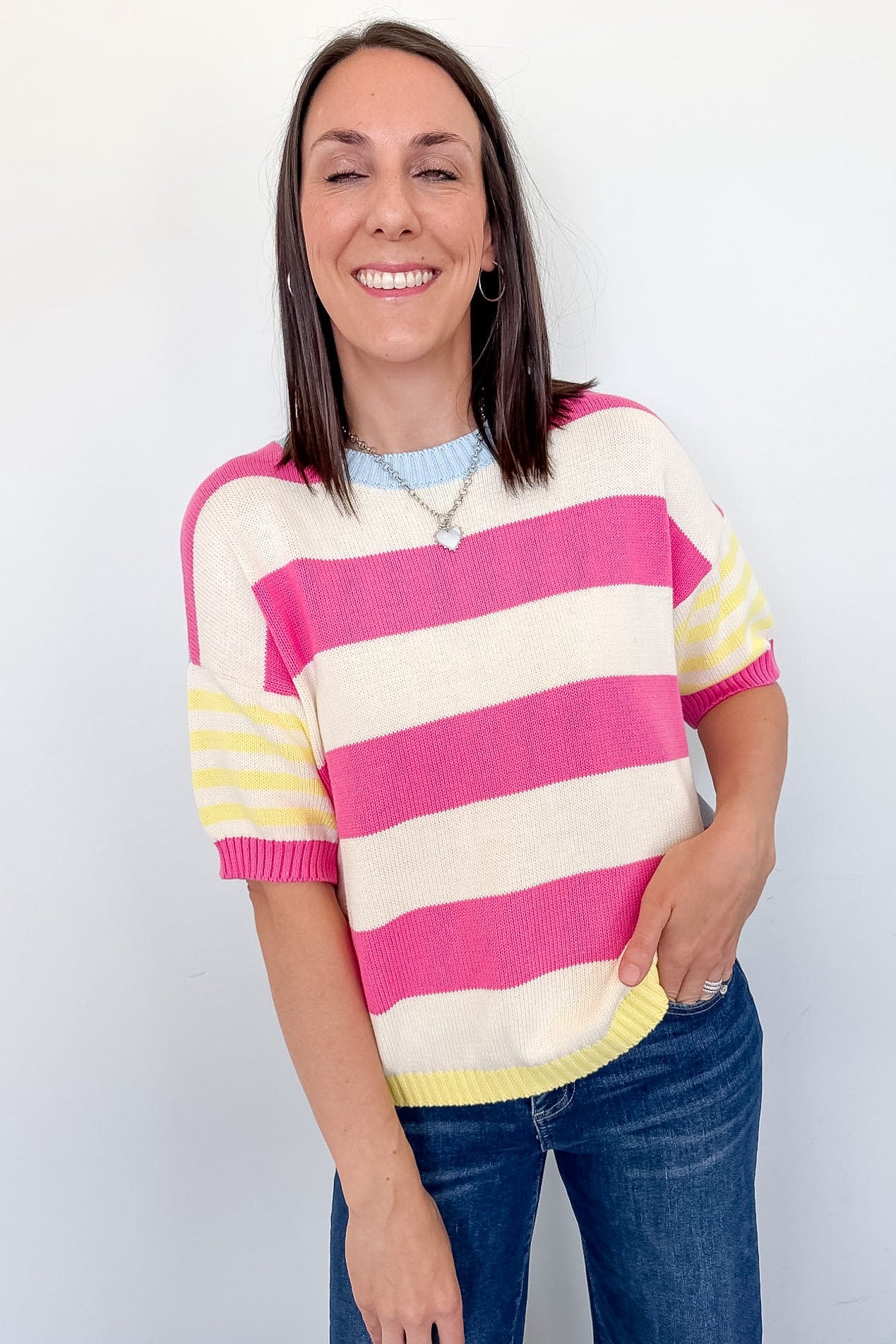 Woman wearing a pink and yellow striped sweater against a white background