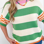 Person wearing a colorful striped sweater with green, orange, and white stripes on a plain background.