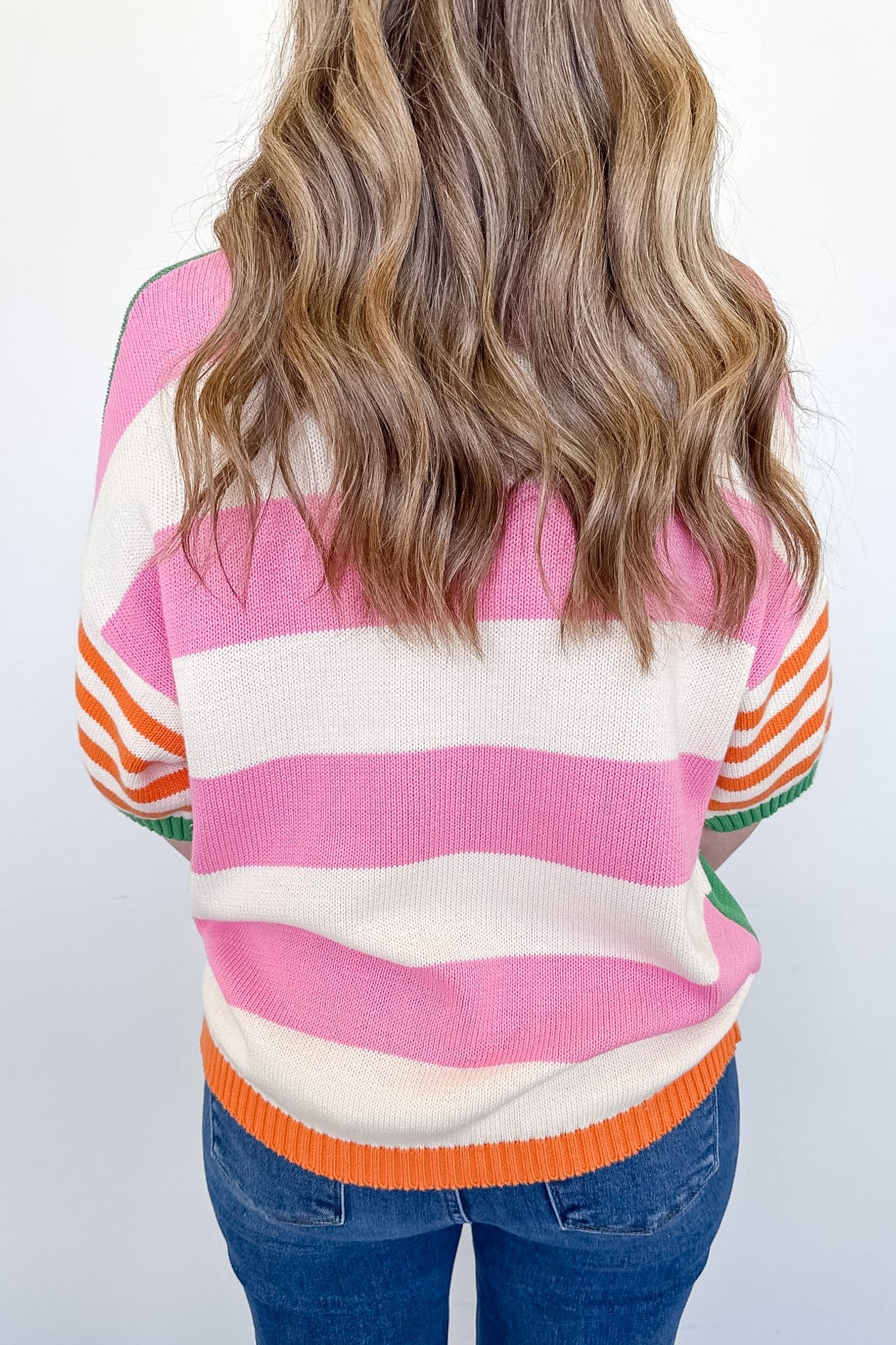 Person wearing a colorful striped sweater with a plain background