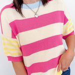 Person wearing a pink and yellow striped sweater against a white background