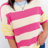 Person wearing a pink and yellow striped sweater against a white background