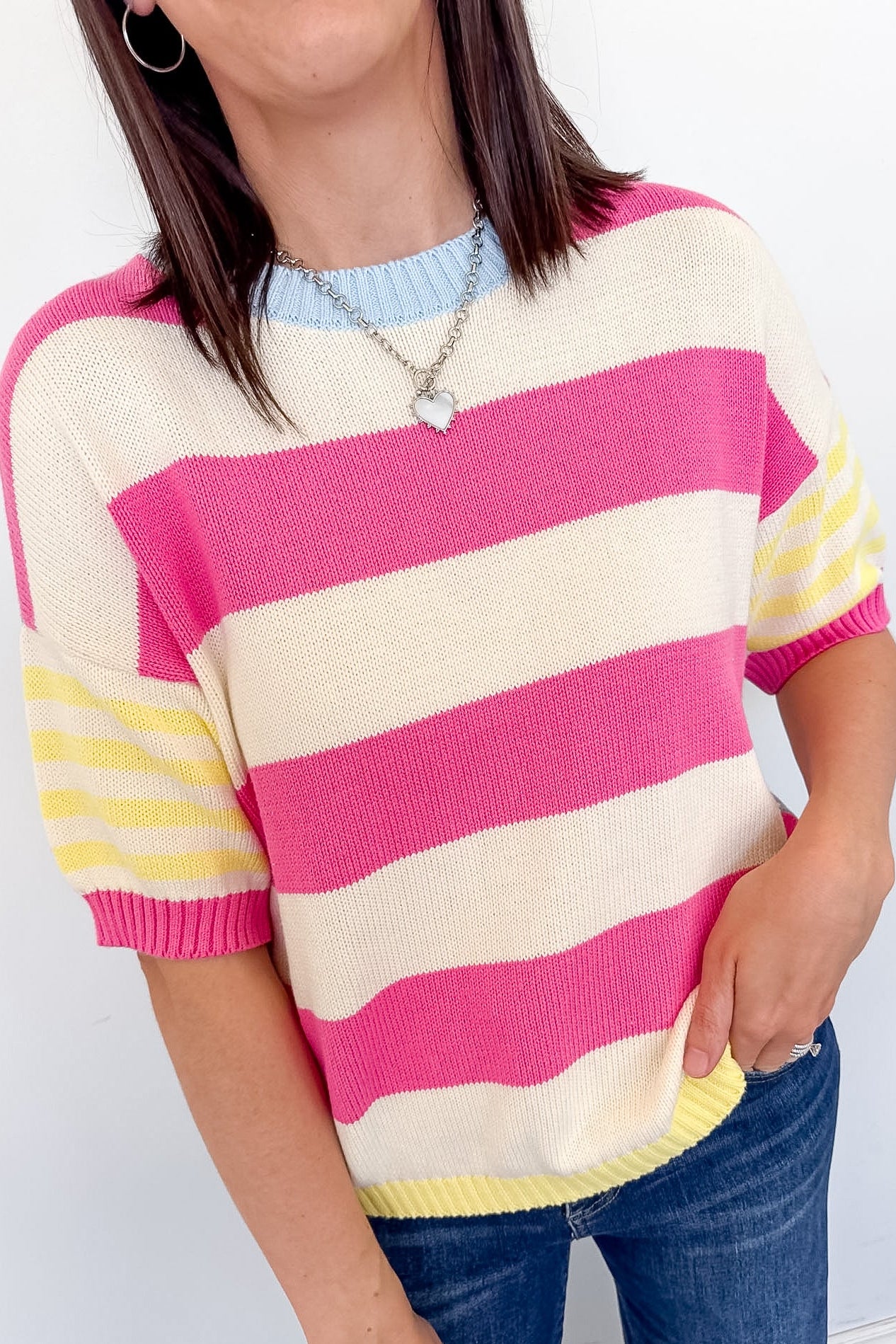 Person wearing a pink and yellow striped sweater against a white background