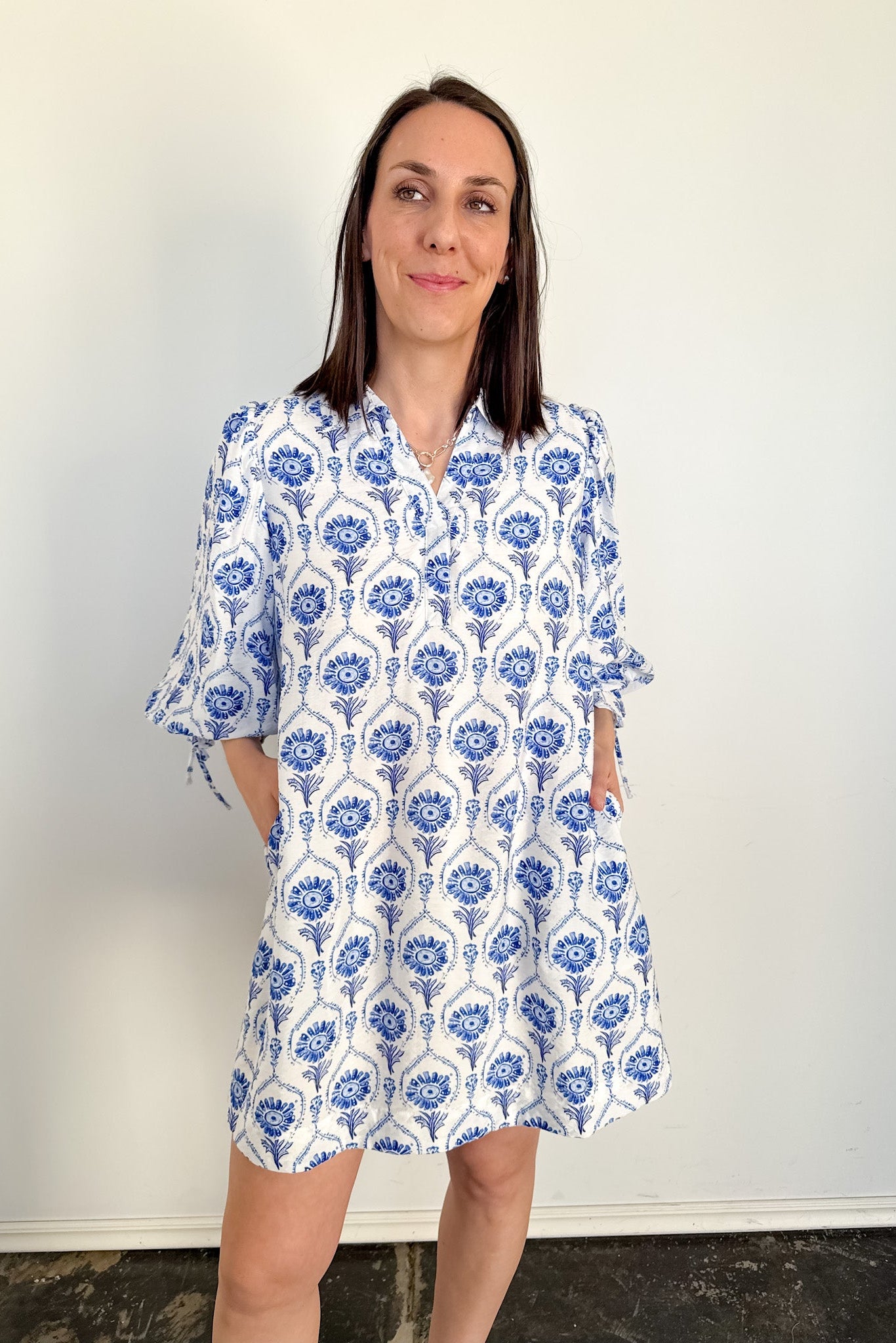 Woman wearing a blue and white patterned dress against a plain background