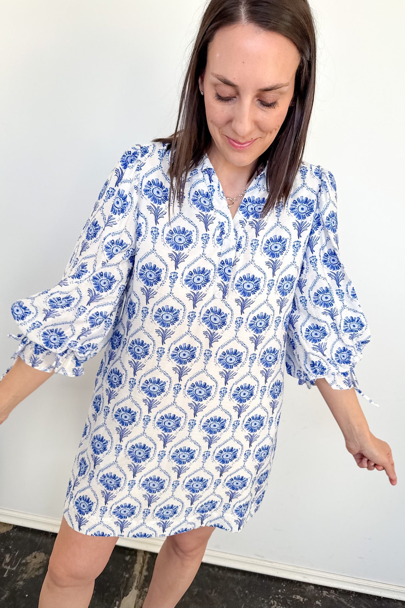 Woman wearing a blue and white floral dress against a plain background