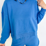 Person wearing a blue sweatshirt and shorts set against a white background