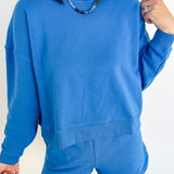 Person wearing a blue sweatshirt and shorts set against a white background